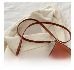 Détail de la bandoulière réglable en cuir et boucle argentée sur un sac porté épaule marron