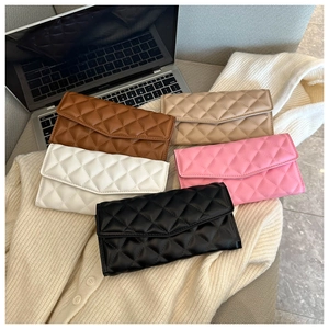 Detailed view of quilted envelope clutch bags in five colors on a white sweater