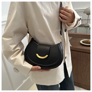 Fashionable black leather crescent shoulder bag with golden hardware shown on model