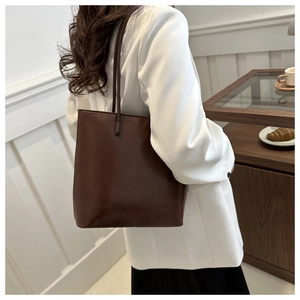 Detail of a dark brown vintage bucket tote bag with sleek straps in a lifestyle setting