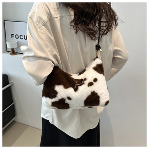 Detailed view of fashionable cow print plush shoulder bag styled on a female model