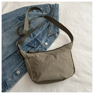 Detail of minimalist olive green nylon crescent crossbody bag on denim background