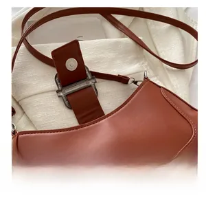 Gros plan sur la boucle magnétique d'un sac baguette en cuir mat marron