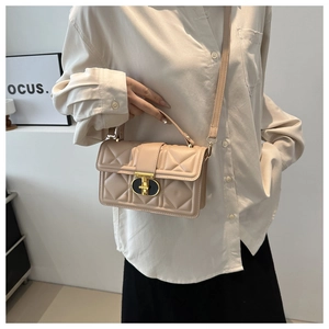 Detail of beige quilted crossbody bag featuring elegant gold metal clasp and leather strap