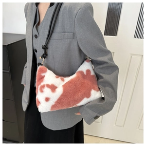 Detail of plush cow print shoulder bag with soft faux fur texture and black leather strap