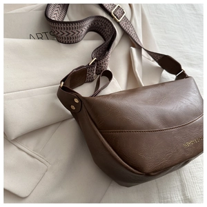Detailed close-up of brown PU leather bag texture with golden fashion logo and strap