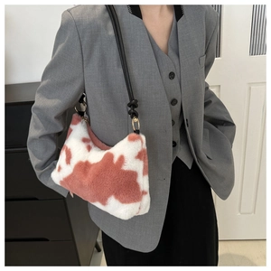 Detail of plush cow print shoulder bag showing faux fur texture and leather strap