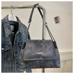 Detail of marble pattern shoulder bag with metal chain strap and flap closure