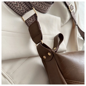 Detail of brown PU leather bag with retro gold buckle and ethnic style woven strap