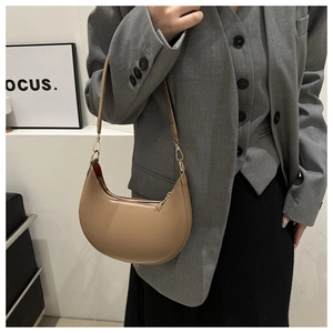 Close-up of khaki crescent shoulder bag with metal zipper and minimalist stitching