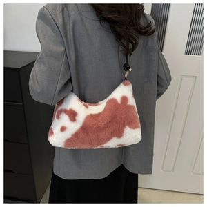 Close-up of pink and white cow print plush shoulder bag with slim black strap