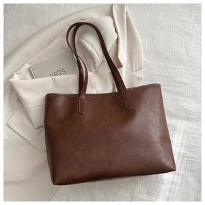 Detailed view of reinforced stitching and retro oil-wax leather texture on brown tote bag