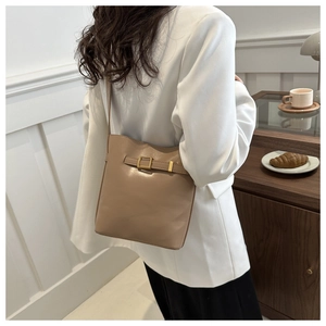 Close-up detail of a chic camel leather bucket bag with a metal buckle and shoulder strap