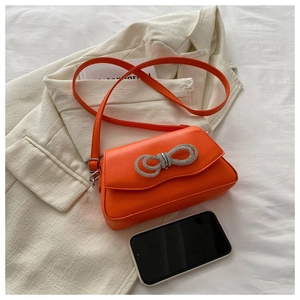 Top view of bright orange square crossbody bag featuring a sparkling rhinestone bow detail