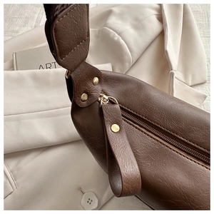 Detailed close-up of brown litchi grain leather bag with gold rivets and stitching