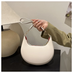 Detail of white crescent bag with gold zipper closure and red inner lining