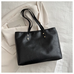 Detail of vintage leather tote bag showing golden rivet reinforcement on shoulder straps