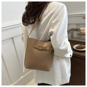 Side view of a khaki PU leather shoulder bucket bag with buckle detail on a model