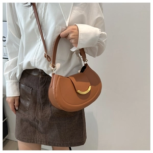 Detailed view of the matte leather finish and gold buckle on a caramel saddle bag