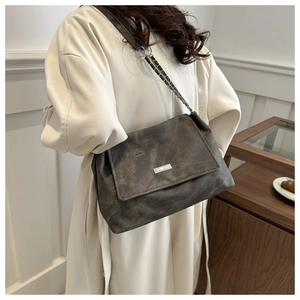 Detail of vintage charcoal leather chain bag featuring silver logo and matte texture