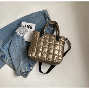 Détail du sac à main matelassé doré avec surpiqûres carrées sur fond de veste en jean