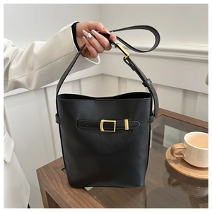 Detail of black matte bucket bag with golden buckle hardware and single shoulder strap