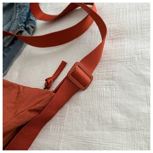 Detail of terracotta crossbody bag showing nylon texture and adjustable strap buckle
