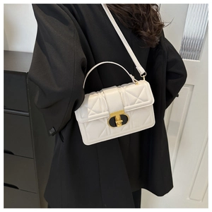 Close-up of white quilted leather texture and golden T-shaped metal lock on the bag
