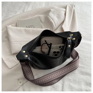 Interior view of black PU dumpling bag with wide woven strap and spacious storage