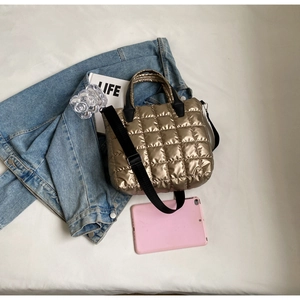 Détail du sac fourre-tout matelassé doré métallisé avec une large bandoulière noire chic