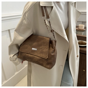 Detail of vintage brown tote bag showing matte texture and silver metallic logo plate