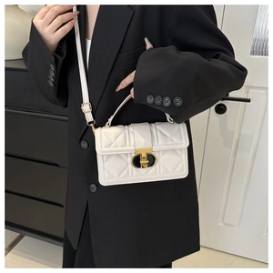 Detail of white quilted crossbody bag featuring unique gold metal lock and shoulder strap