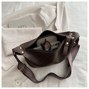Detail of dark brown faux leather crescent bag with wide jacquard strap and internal capacity