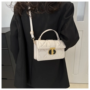Detail of quilted leather crossbody bag featuring a golden metallic twist lock closure