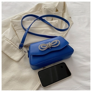 Detail of royal blue leather crossbody bag with sparkling rhinestone bow on the flap