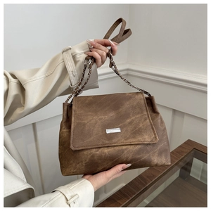 Detail showing vintage brown leather texture and silver MIKXAIQI logo on a shoulder bag