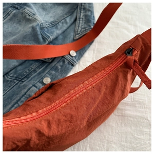 Detail of caramel orange nylon crossbody bag with textured fabric and wide strap
