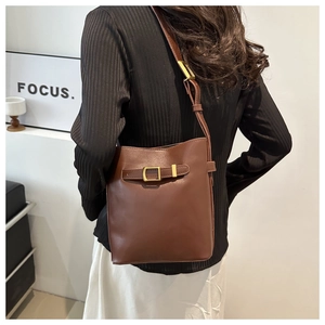 Detail of dark brown leather bucket bag with retro gold buckle and adjustable strap
