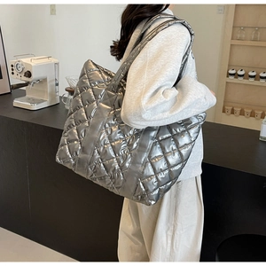 Detailed view of silver quilted tote bag with metallic finish shown in a cafe setting