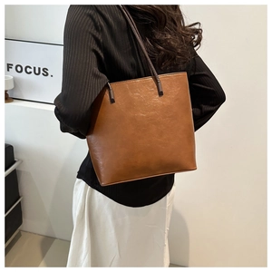 Vintage dark brown faux leather bucket bag shown as a crossbody on a stylish model