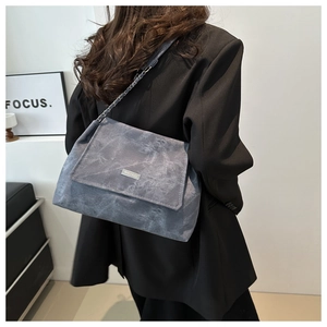 Detail of grey-blue marble textured flap bag with silver metal logo and leather chain strap