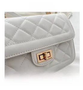 Détail d'un sac en cuir blanc matelassé avec un fermoir rotatif doré de style rétro