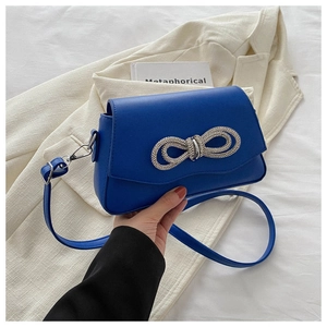 Close-up of royal blue crossbody bag with sparkling rhinestone bow and silver clasp