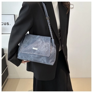 Blue marble textured shoulder bag with silver chain strap shown on black suit jacket