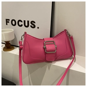 Détail du sac baguette rose fuchsia avec une grande boucle argentée sur socle blanc