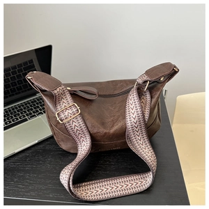 Detailed shot of dark brown pebbled leather texture and woven shoulder strap on the bag