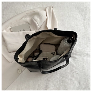 Top view of spacious black faux leather tote bag interior with everyday essentials