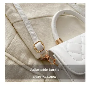 Détail de la boucle dorée réglable et du fermoir sur le sac blanc matelassé