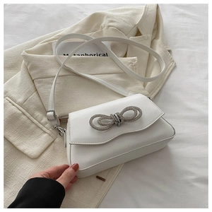 Detailed view of white square bag featuring a crystal bow buckle and smooth PU finish