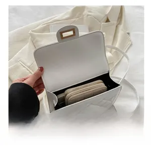 Détail du sac bandoulière blanc matelassé montrant la capacité avec un portefeuille beige